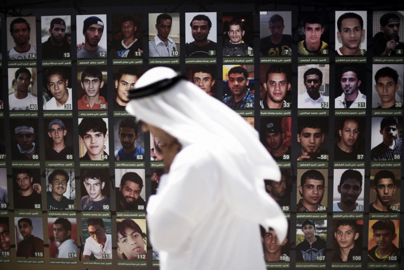 A Bahraini man walks past portraits of men reportedly detained after attending anti-government protests