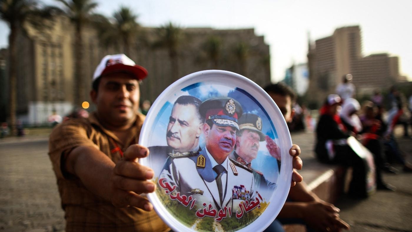 Célébrant l’arrivée de Sissi à la présidence, un Égyptien montre une assiette ornée des portraits de Nasser, Sissi et Sadate (de gauche à droite), sur la place Tahrir au Caire, le 3 juin 2014 (AFP)