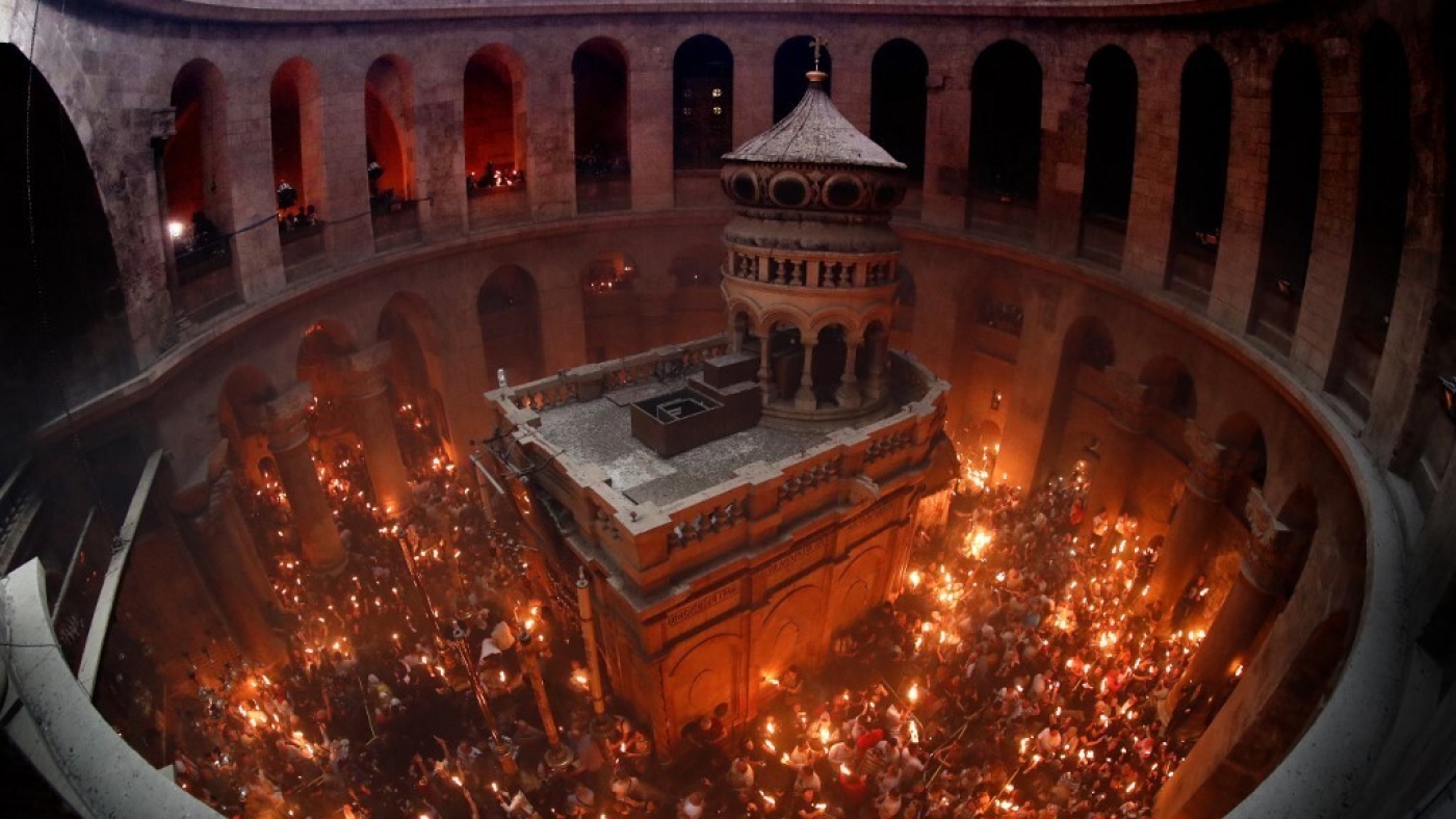 Assemblés dans l’église du Saint-Sépulcre, des chrétiens orthodoxes tiennent des cierges allumés dans le feu sacré, dans la vieille ville de Jérusalem (AFP)