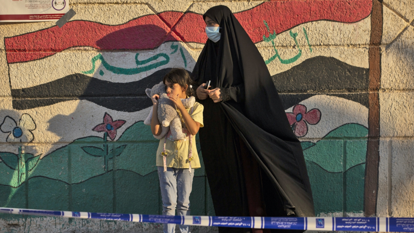 An Iraqi woman and a girl are pictured outside a polling station in the southern city of Basra, on 10 October 2021 (AFP)