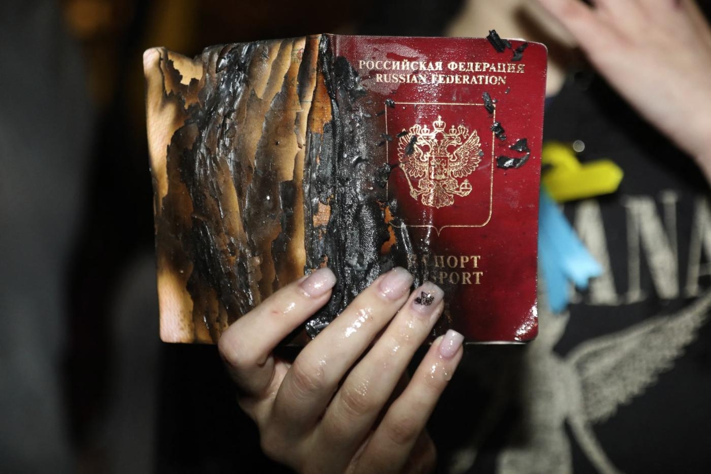 Une femme brandit son passeport russe après l’avoir brûlé lors d’une manifestation devant l’ambassade de Russie à Tel Aviv, le 24 février 2022 (AFP)