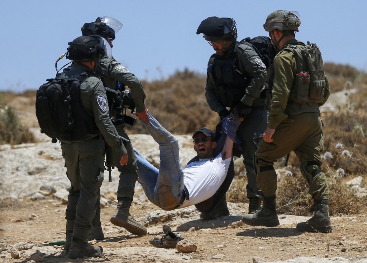 Israeli forces remove a protester during a demonstration by Palestinians in Masafer Yatta, in the Israeli-occupied West Bank, 1 July 2022 (AFP)
