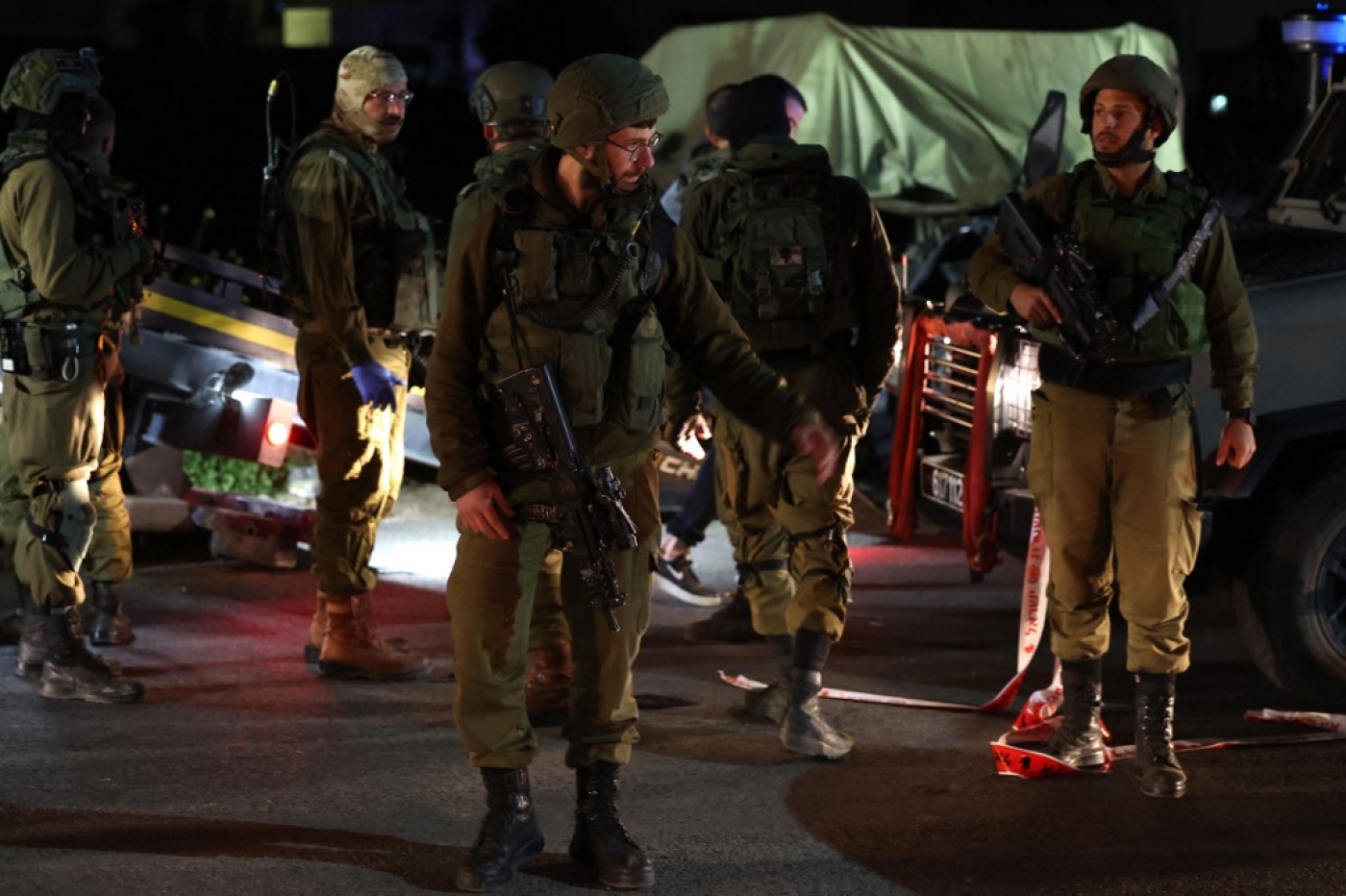 Israeli soldiers gather at the site of a ramming attack near the town of Beit Ummar, north of Hebron city in the occupied West Bank, on 1 April 2023 (AFP)