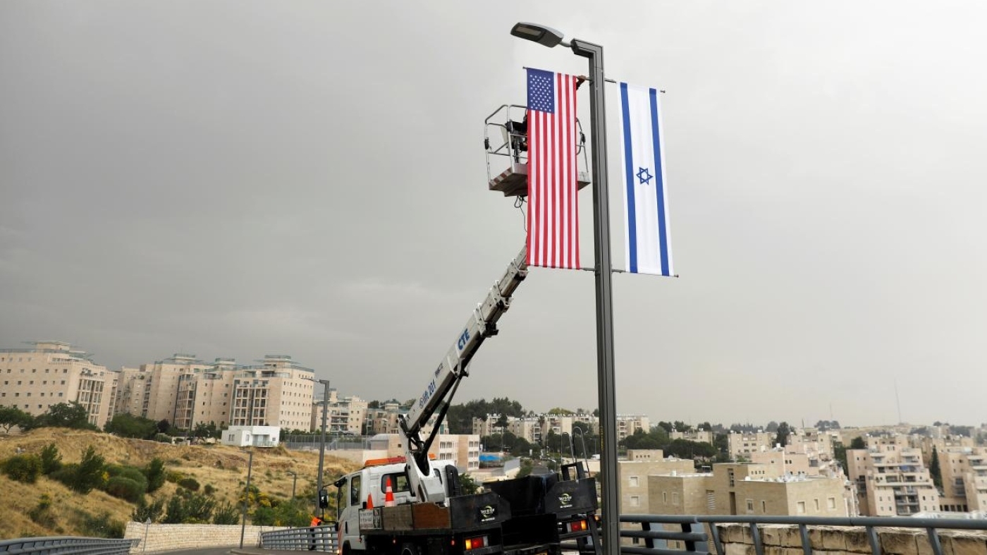 A worker on a crane hangs a US flag next to an Israeli flag, next to the entrance to the US consulate in Jerusalem on 7 May 2018.