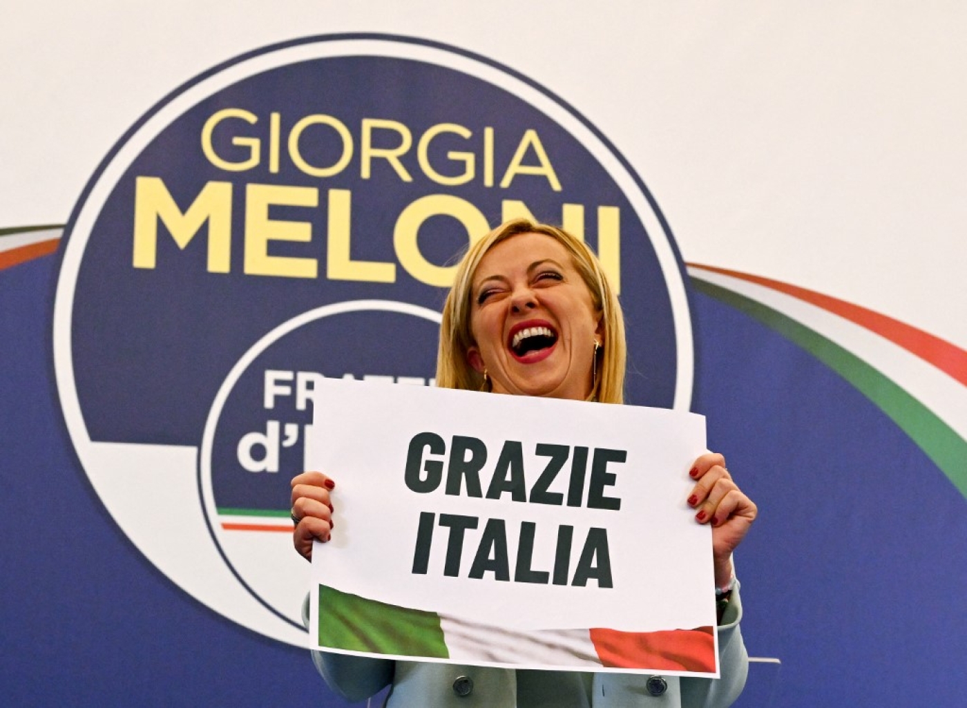 Giorgia Meloni, leader of Italian far-right party Fratelli d'Italia (Brothers of Italy), holds a placard reading 'thank you Italy', at her campaign headquarters in Rome, on 26 September 2022 (AFP)