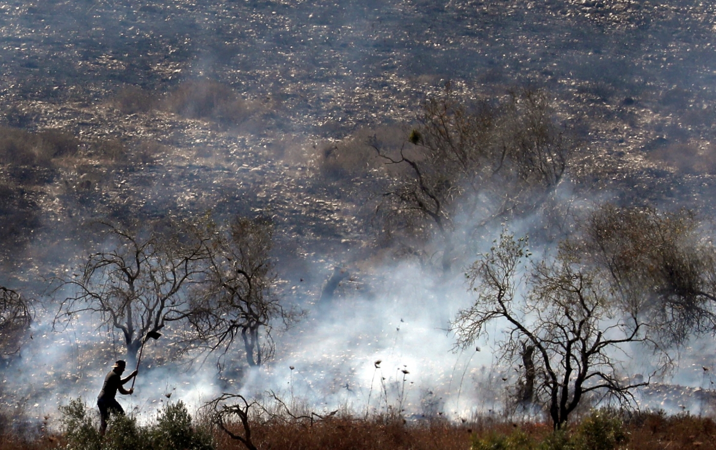 Un Palestinien combat un incendie qui aurait été allumé par des colons israéliens dans une oliveraie en 2019 (AFP)