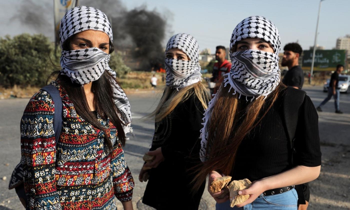 Des Palestiniennes masquées d’un keffieh traditionnel près de Ramallah en Cisjordanie occupée (AFP/Abbas Momani)