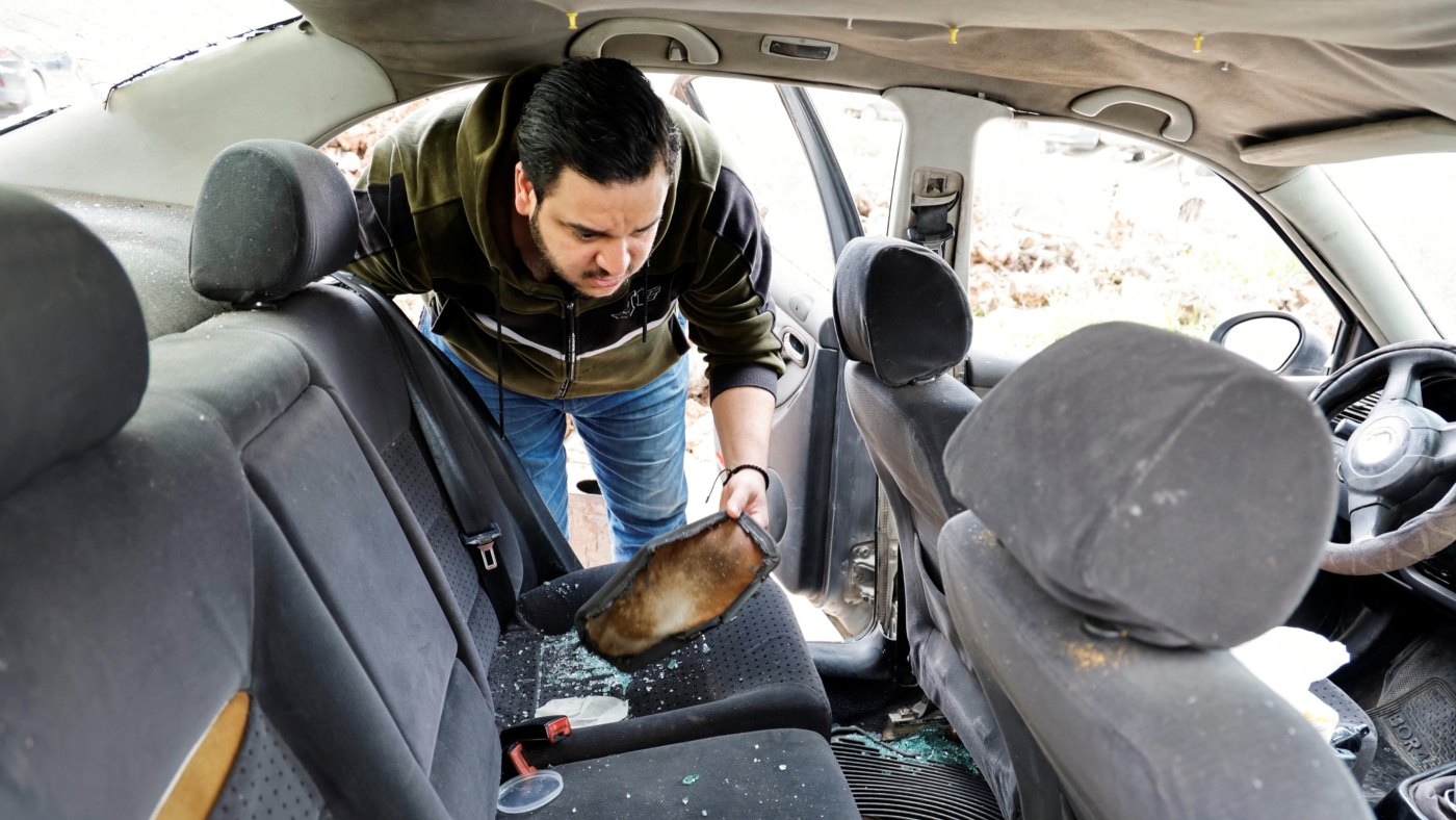 Palestinian Omar Khalifa inspects his car, which was attached by Israeli settlers while he was in it with his family in Huwwara on 7 March 2023 (Reuters)