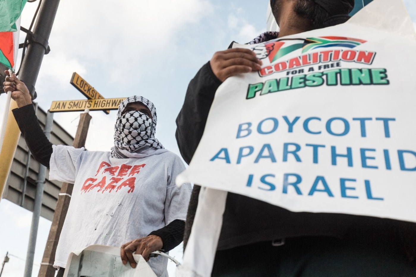 Pro-Palestinian supporters hold placards reading 'Boycott Apartheid Israel' during a protest to condemn the Israeli air strikes on Gaza, Durban, South Africa, 18 May 2021 (AFP)