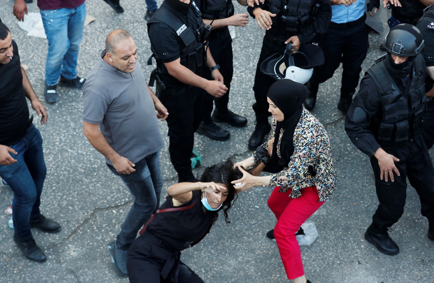Une manifestante tombe à terre lors d’une échauffourée avec un policier palestinien au cours d’une manifestation en réaction à la mort de Nizar Banat, le 26 juin 2021 à Ramallah, en Cisjordanie occupée (Reuters)