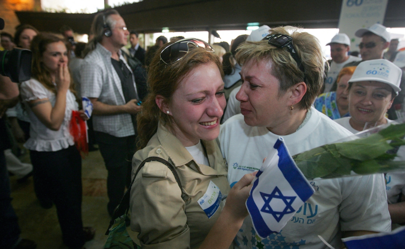 Des sympathisants tenant des fleurs et des drapeaux israéliens enlacent une immigrée russe à son arrivée à l’aéroport Ben Gourion de Tel Aviv, le 5 mai 2008 (AFP)
