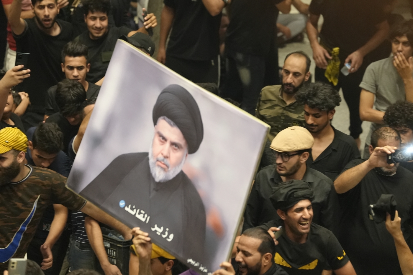 Sadrists hold up a photo of Shia Cleric Muqtada al-Sadr during protest outside Iraq's parliament in Baghdad (MEE/Azhar Al-Rubaie)