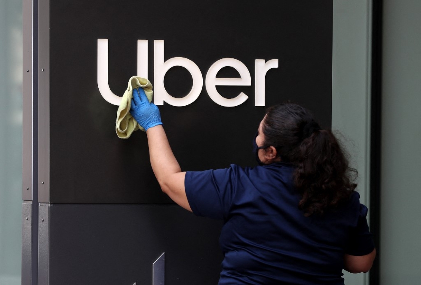 Une employée nettoie l’enseigne d’Uber, au siège de l’entreprise, le 18 mai 2020 à San Francisco, Californie (AFP)