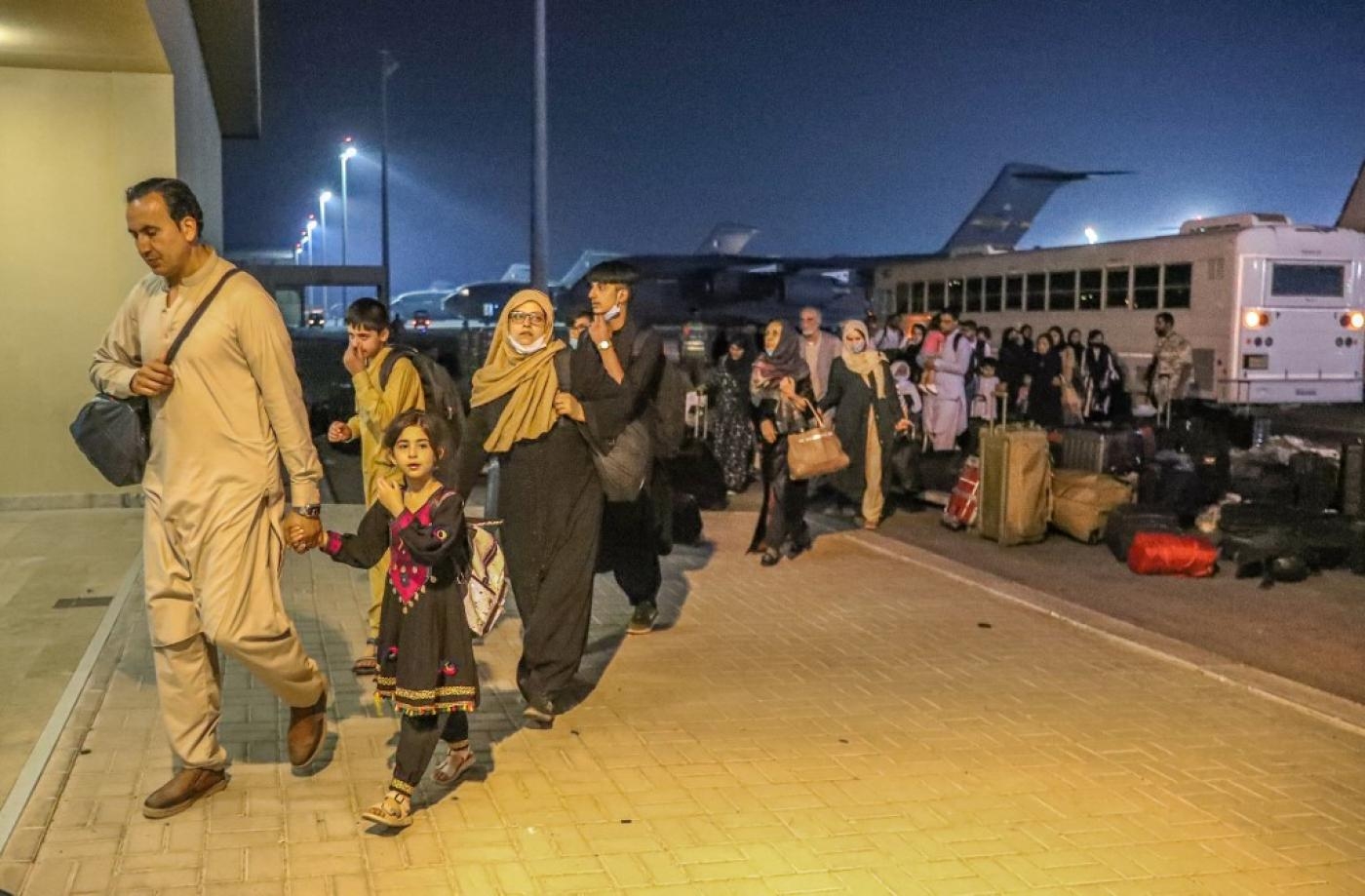Des personnes évacuées d’Afghanistan arrivent à la base aérienne d’al-Udeid au Qatar, le 21 août 2021 (Bureau de communication du gouvernement qatari/AFP)