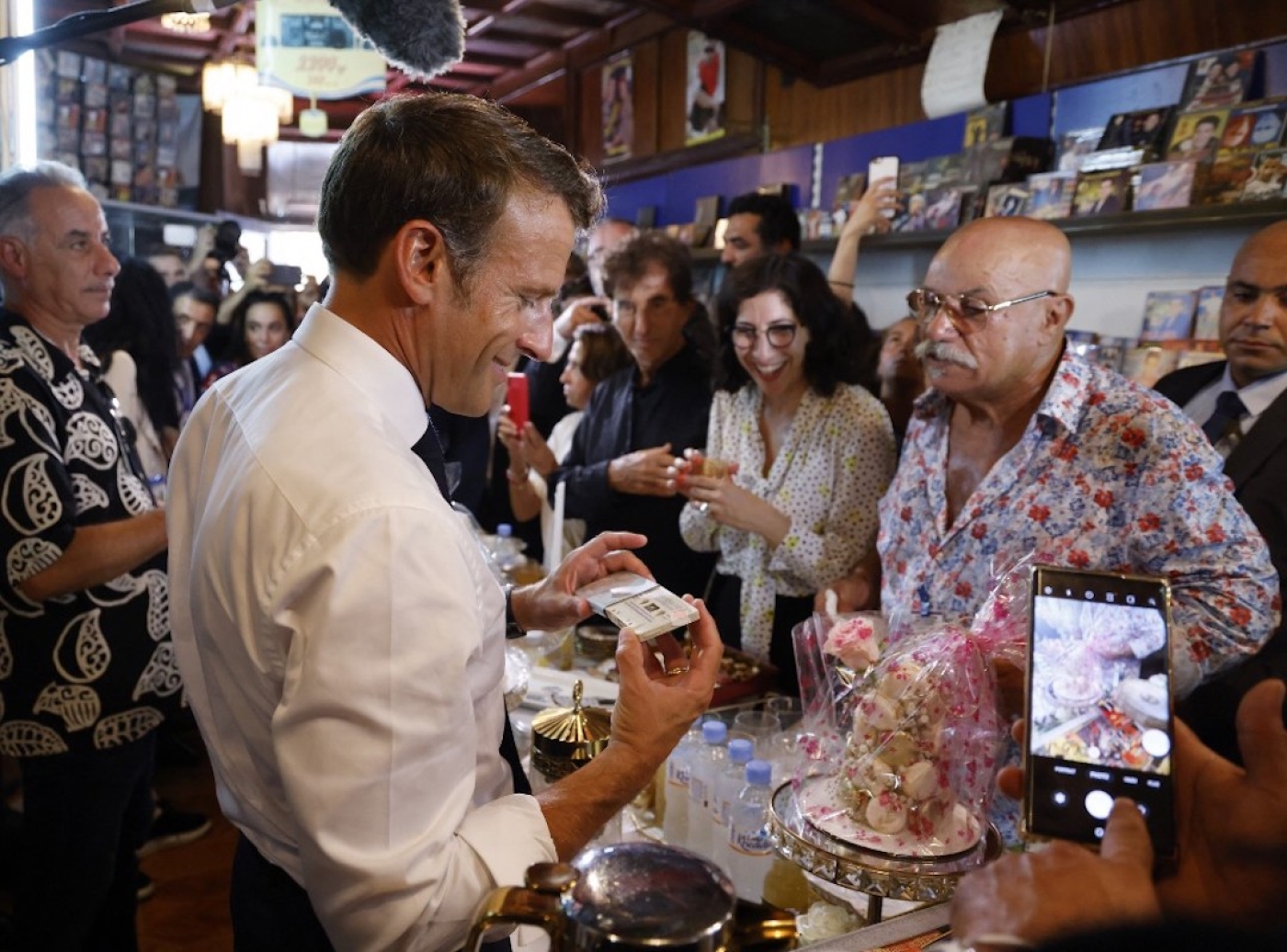 Le président français Emmanuel Macron visite Disco Maghreb, le label mythique de la musique raï, devant son propriétaire, Boualem Benhaoua (à droite), à Oran le 27 août 2022 (AFP/Ludovic Marin)