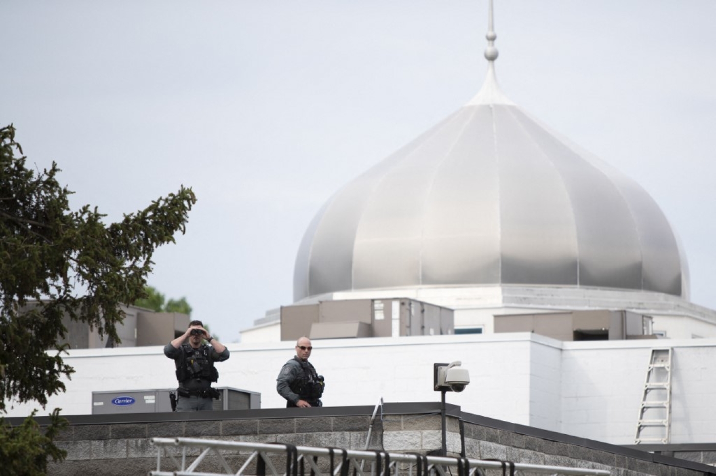 Police officers stand on the roof of a mosque as Canada Prime Minister Justin Trudeau attends a vigil for the victims of the deadly vehicle attack in London, Ontario on 8 June 2021