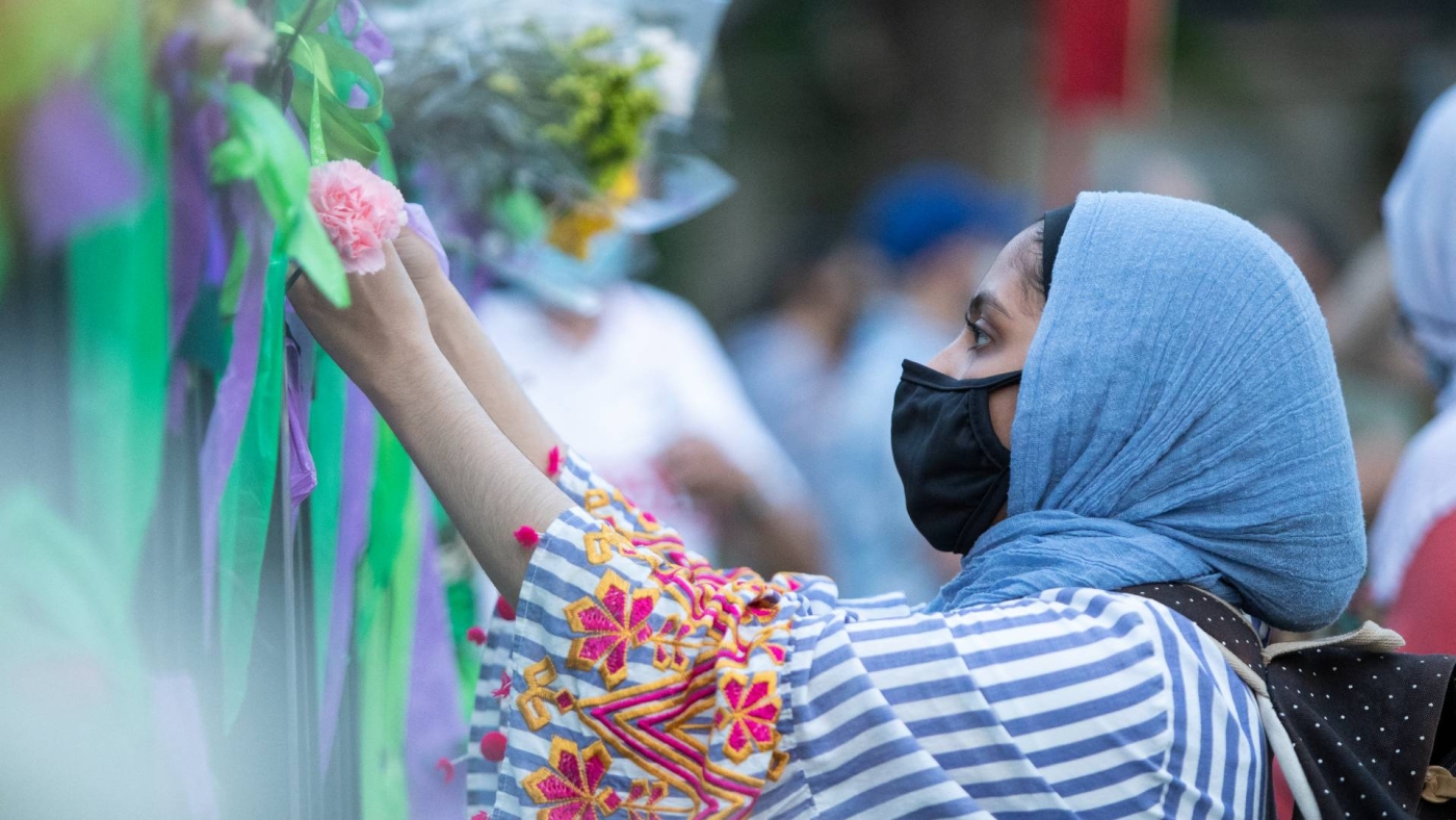 A young woman puts a flower on the fence of the London Muslim Mosque during a march, after a man driving a pickup truck struck and killed four members of a Muslim family in London, Ontario, Canada on 11 June 2021.