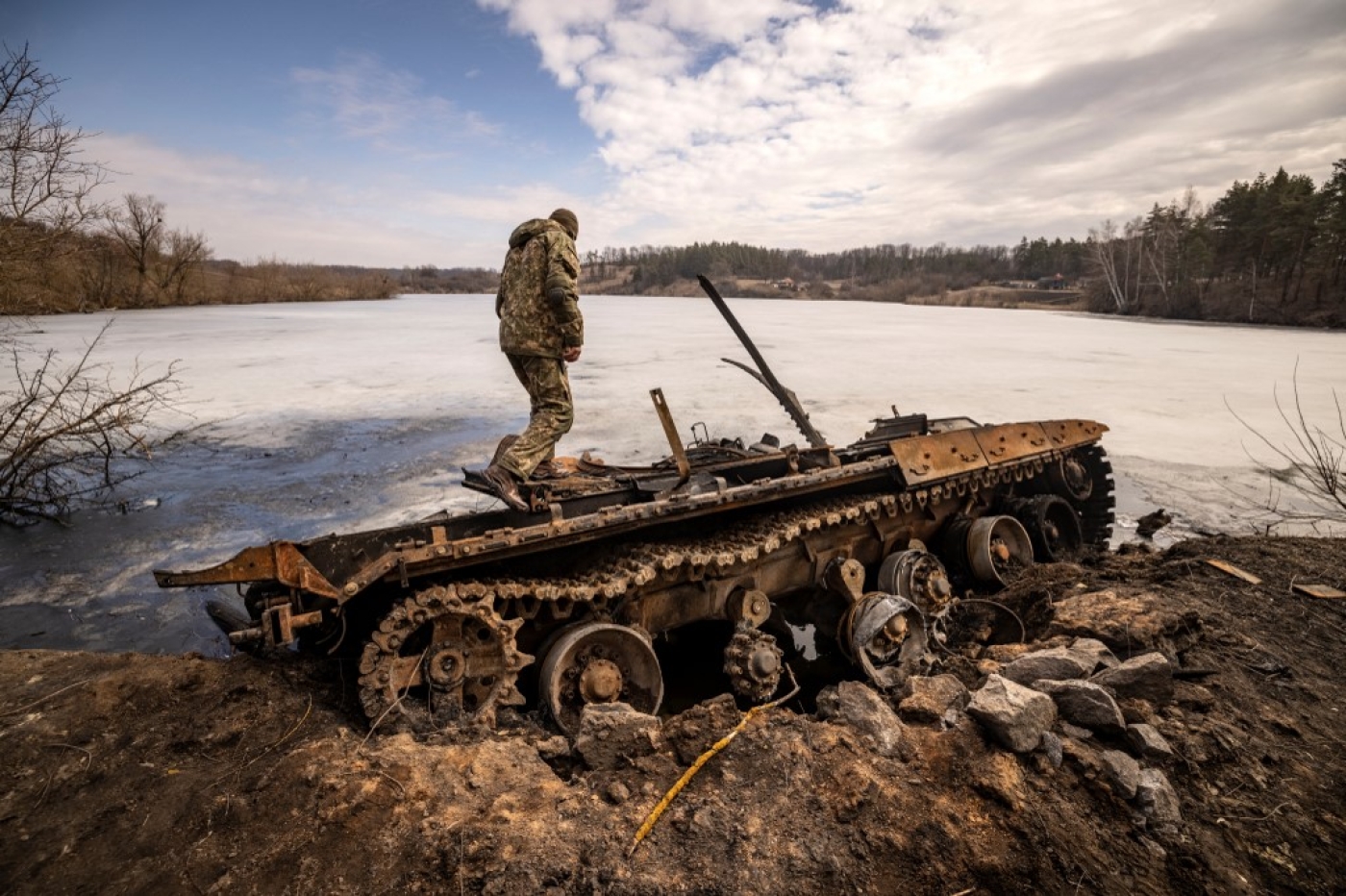 Un militaire ukrainien se tient près d’un char russe détruit dans la ville de Trostyanets, dans le nord-est du pays, le 29 mars 2022 (AFP/Fadel Senna)
