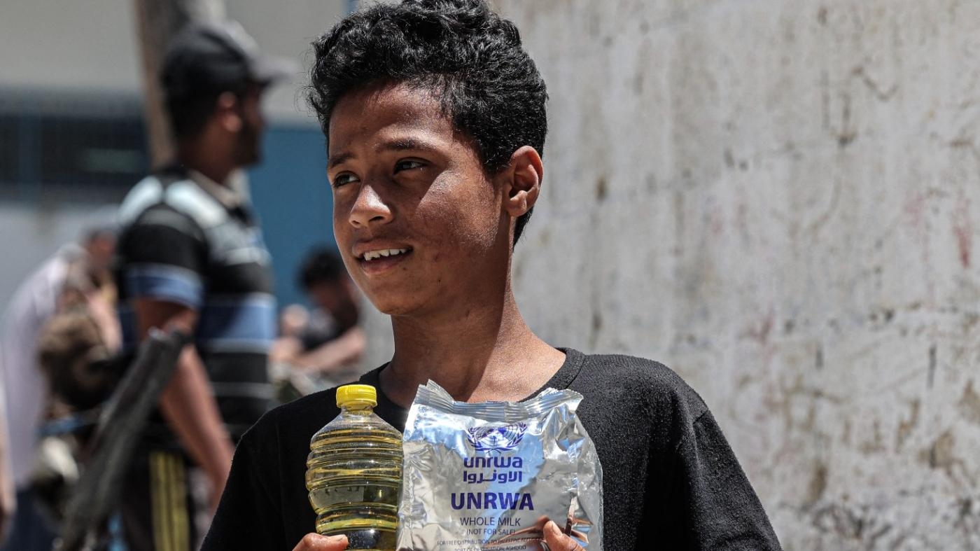 Un garçon tient une bouteille d’huile et une ration alimentaire de l’agence des Nations unies pour les réfugiés palestiniens, le 28 janvier 2021 à Gaza (AFP)