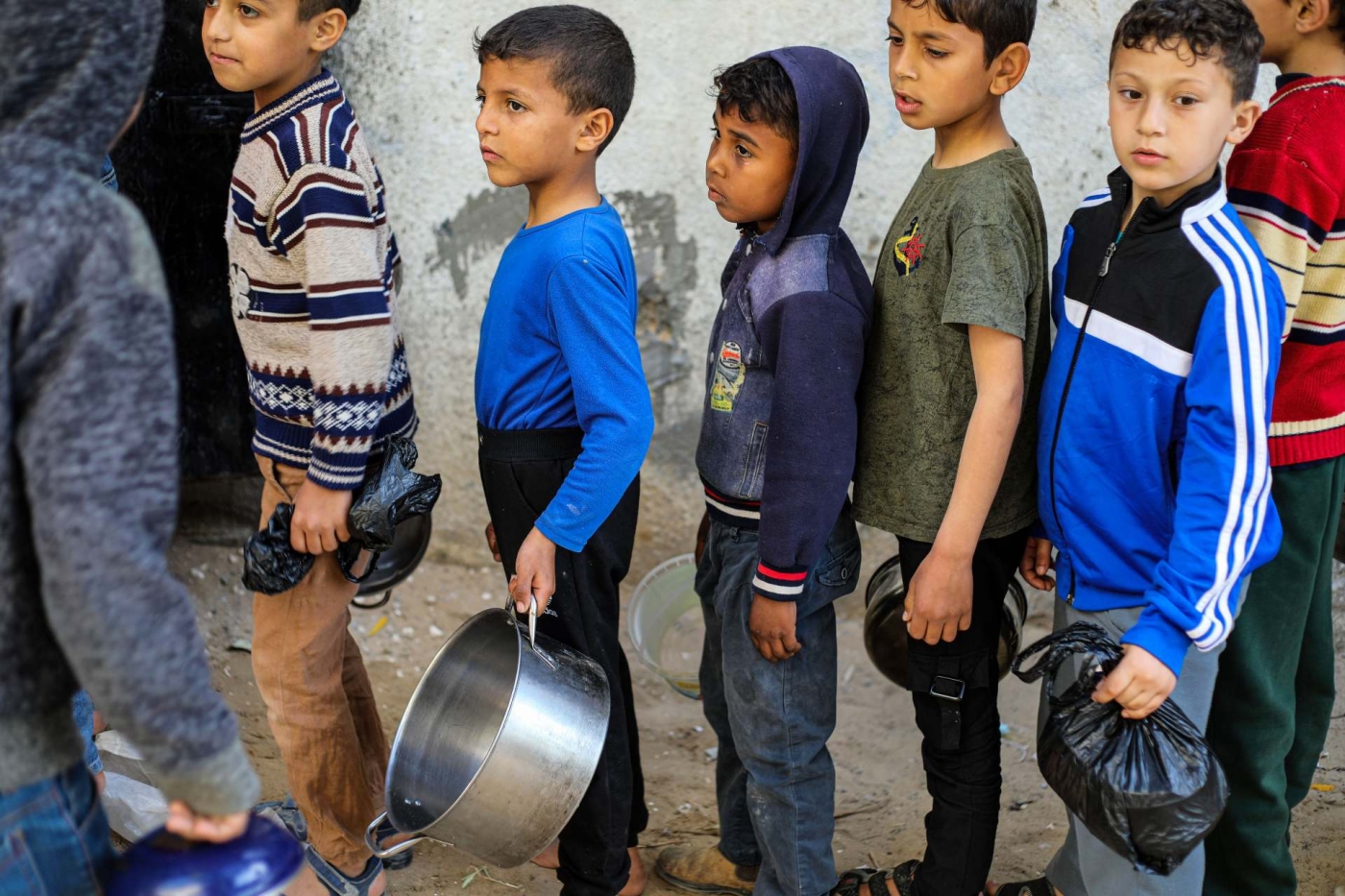 Children in Gaza's Al-Nuseirat refugee camp queue for soup provided by a charity during Ramadan, in April 2022 (Reuters)