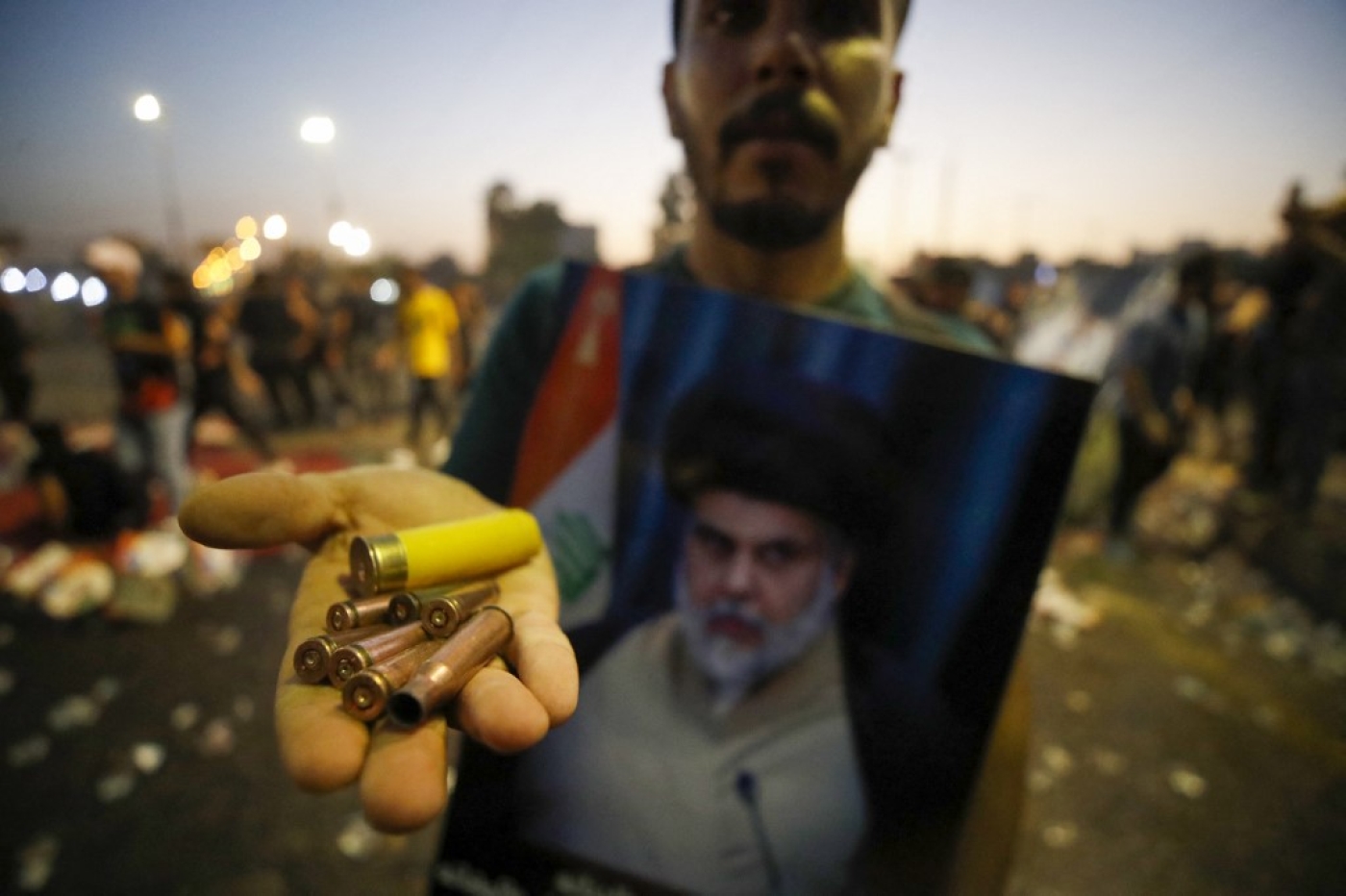 Un partisan du religieux chiite irakien Moqtada Sadr montre des douilles et une cartouche de fusil de chasse dans la capitale Bagdad, le 29 août 2022 (AFP/Ahmad Al-rubaye)