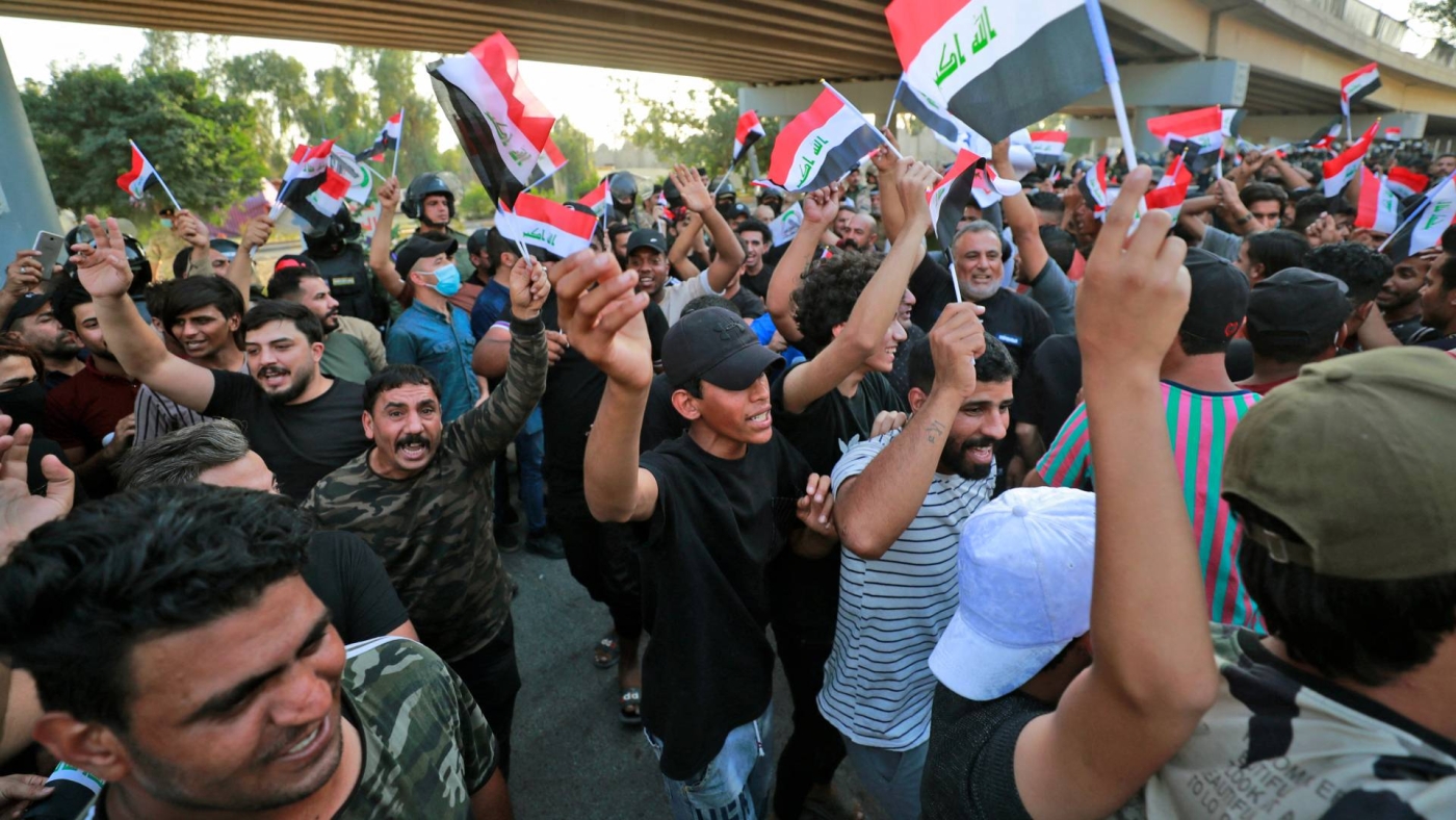 Iraqi protesters lift national flags during a demonstration against last month's election result, near an entrance to Baghdad's Green Zone on 5 November 2021.