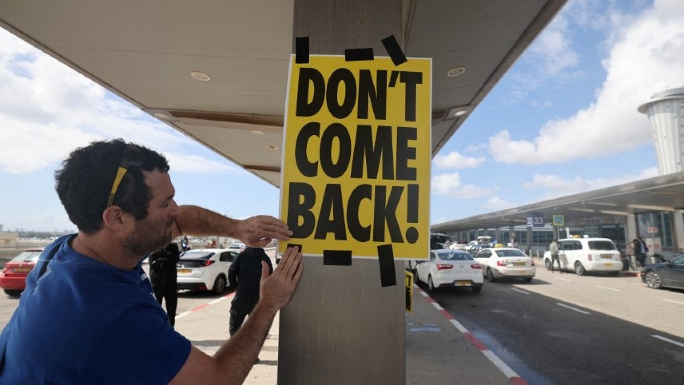 An anti-government protester sticks a poster with the slogan "Don't Come Back" during a demonstration outside Ben Gurion airport near Tel Aviv against the controversial judicial reform bill as Prime Minister Benjamin Netanyahu heads to Germany on an official visit on 15 March 2023 (AFP)