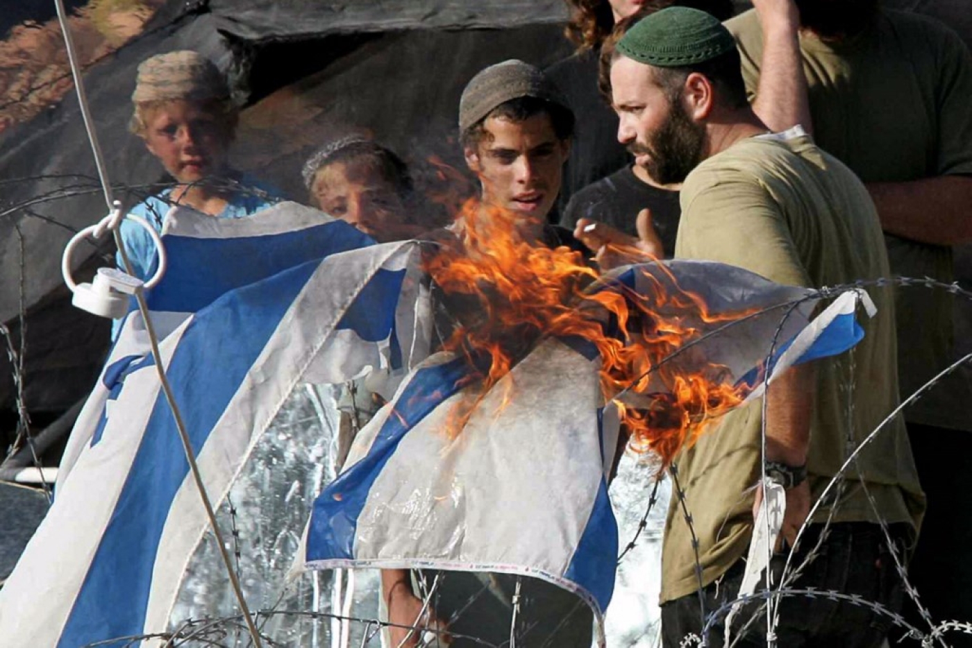 Des colons juifs et leurs partisans retranchés à l’intérieur de la colonie de Homesh en Cisjordanie brûlent un drapeau israélien, 23 août 2005, protestant contre leur évacuation par les autorités israéliennes (AFP/Thomas Coex) 