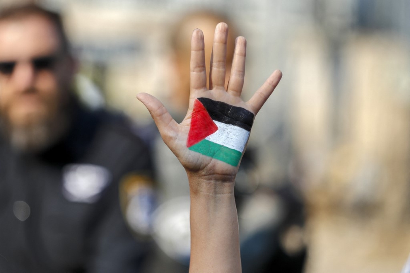 A demonstrator raises her hand, painted with the colours of the Palestinian flag, during a protest in Jerusalem on 30 July 2021 (AFP)