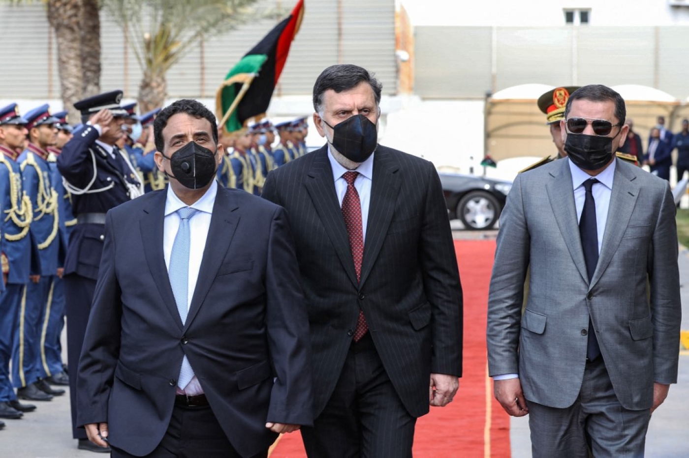 Le chef du conseil présidentiel libyen Mohamed al-Manfi (à gauche) et le Premier ministre Abdel Hamid Dbeibah (à droite) arrive avec le dirigeant du GNA Fayez al-Sarraj pour le transfert de pouvoir à Tripoli, le 16 mars (AFP)