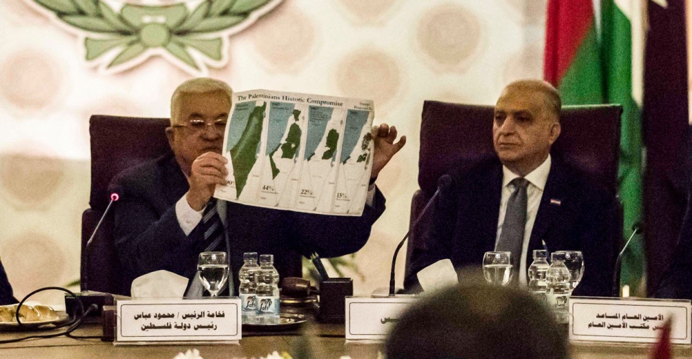 Palestinian president Mahmud Abbas (L) holds a placard of maps showing the loss over time of Palestinian territory as he attends an Arab League emergency meeting in Cairo on 1 February 2020.