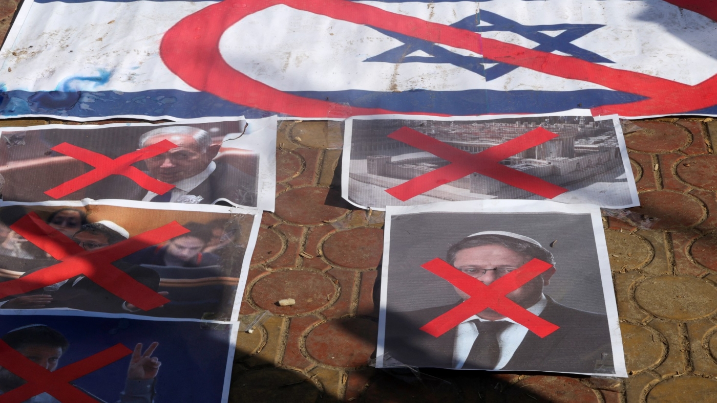Palestinian protesters burn the Israeli flag and defaced posters depicting Netanyahu and Knesset members Smotrich and Itamar Ben-Gvir against Israel and in support of Jerusalem's Al-Aqsa Mosque in Gaza on 18 December, 2022 (AFP)