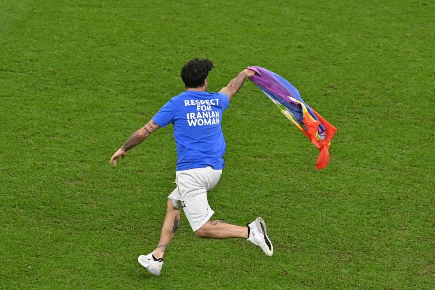 Un homme envahit le terrain tenant un drapeau LGBTQI+ lors du match de football du groupe H entre le Portugal et l’Uruguay au stade Lusail, au nord de Doha, le 28 novembre 2022 (AFP/Glyn Kirk)