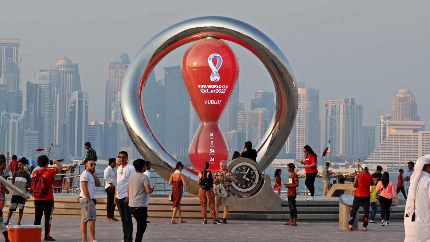 Des personnes passent devant le compte à rebours de la Coupe du monde 2022, le 20 octobre 2022 à Doha, capitale du Qatar (AFP)
