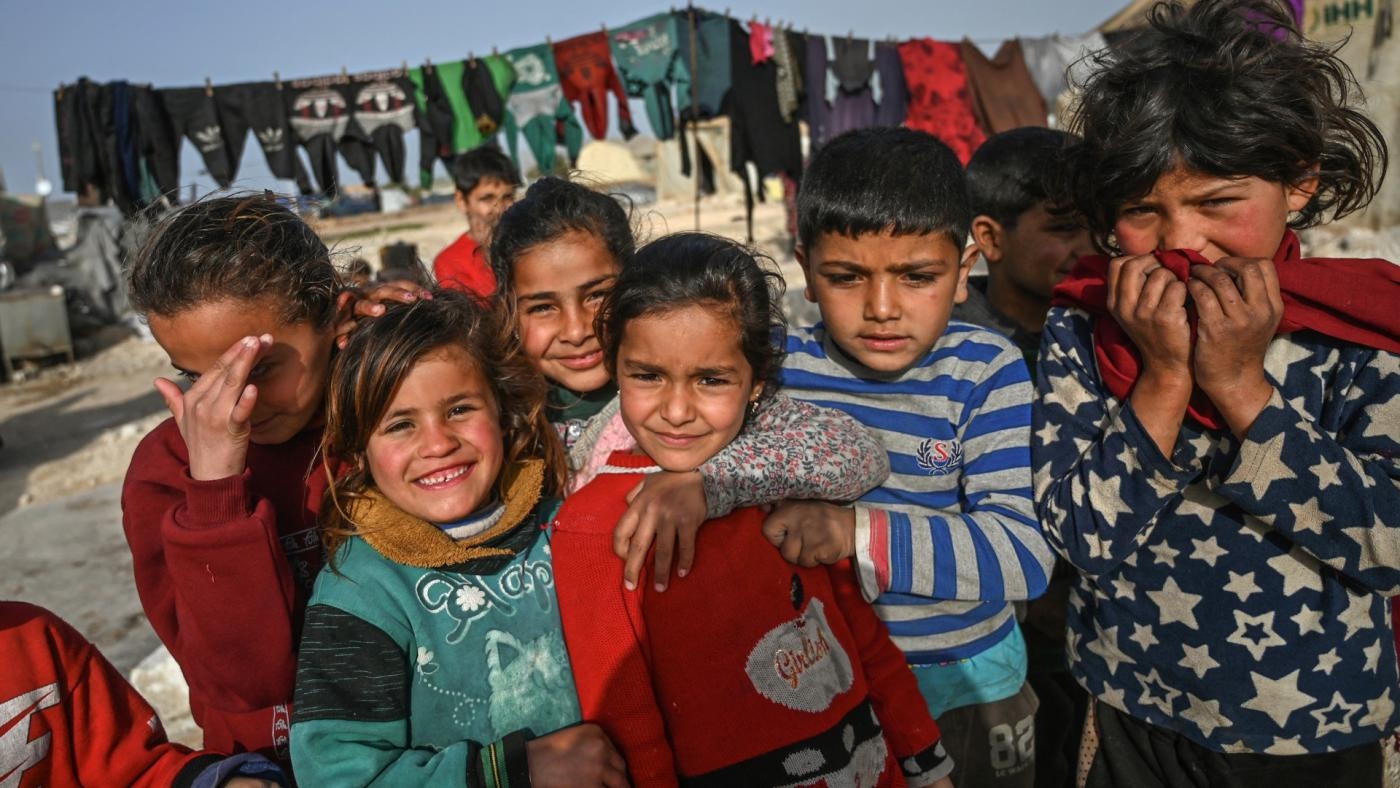 Des enfants syriens déplacés posent pour une photo dans un camp à la frontière avec la Turquie dans la province d’Idleb, dans le Nord-Ouest de la Syrie, le 10 mars 2020 (AFP)