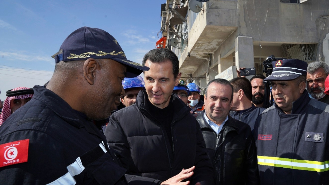 Syrian President Bashar Assad, second left, speaks with an Algerian rescue team at the site of destroyed buildings following devastating earthquake in Aleppo province on 10 February 2023.