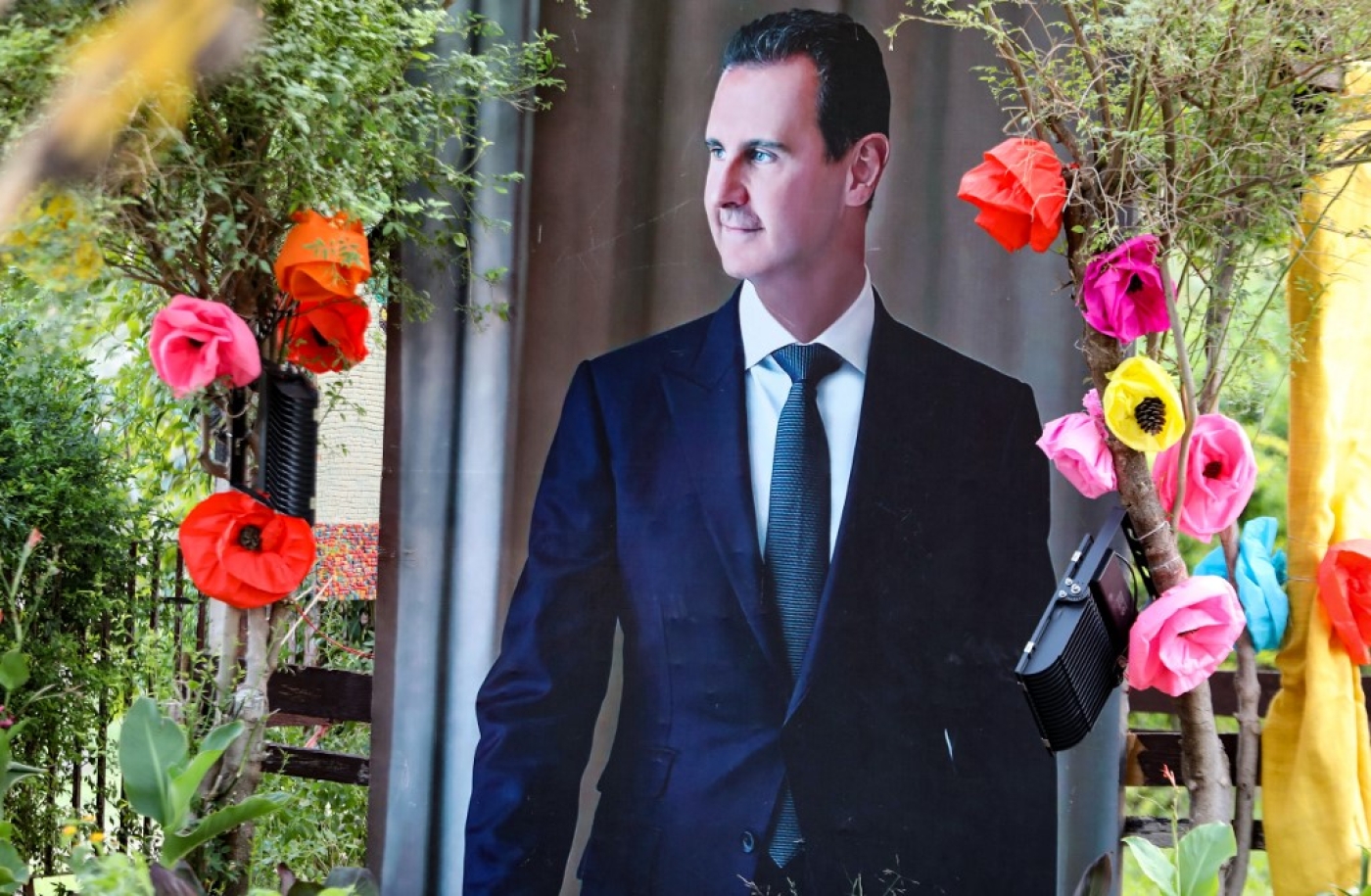 Un poster de Bachar al-Assad décoré avec des fleurs en papier, à Damas, le 22 juin 2022 (AFP/Louai Beshara)