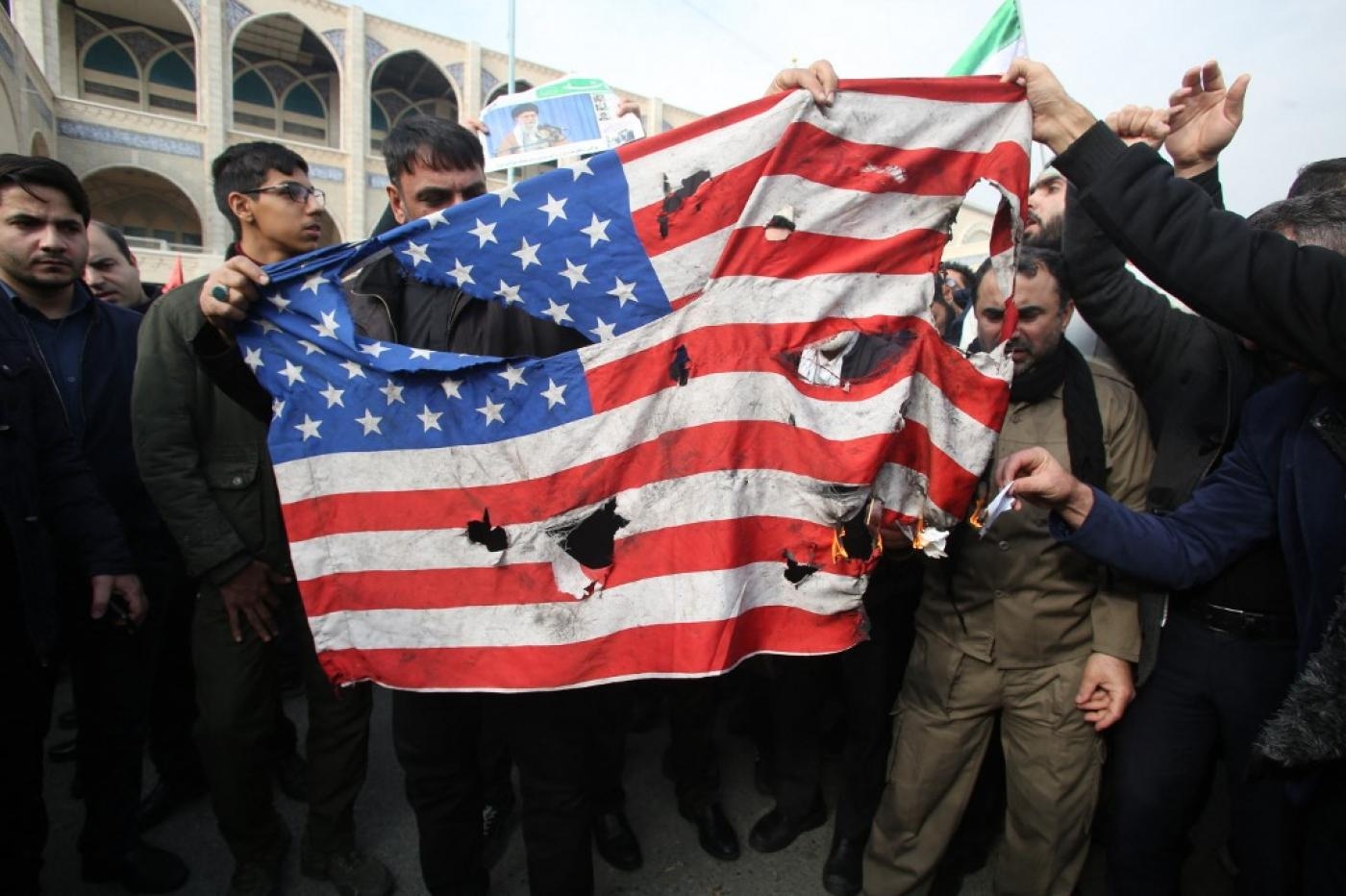 Des Iraniens détruisent un drapeau américain au cours d’une manifestation à Téhéran, en janvier 2020 (AFP)
