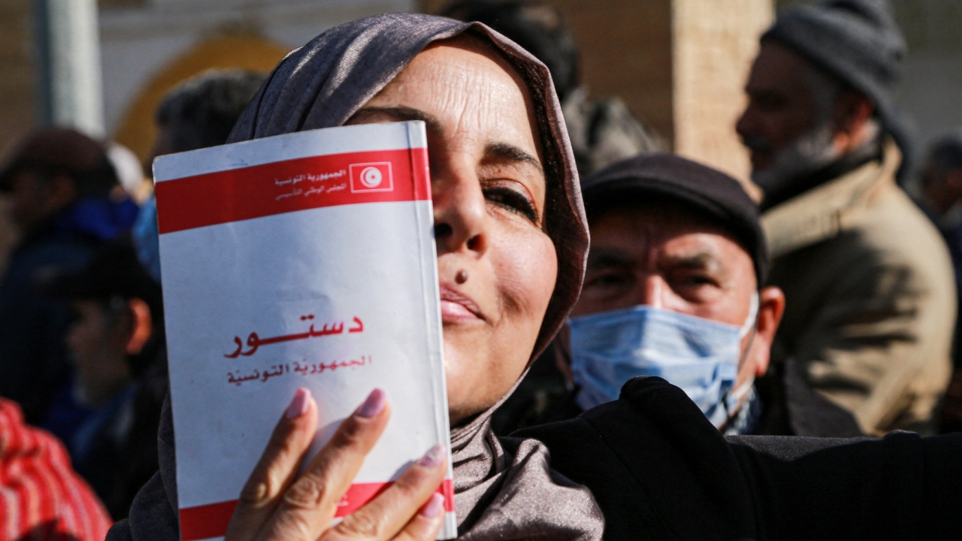 A woman holds a copy of the Tunisian constitution during a demonstration in Tunis against President Kais Saied's decrees on 13 February 2022.