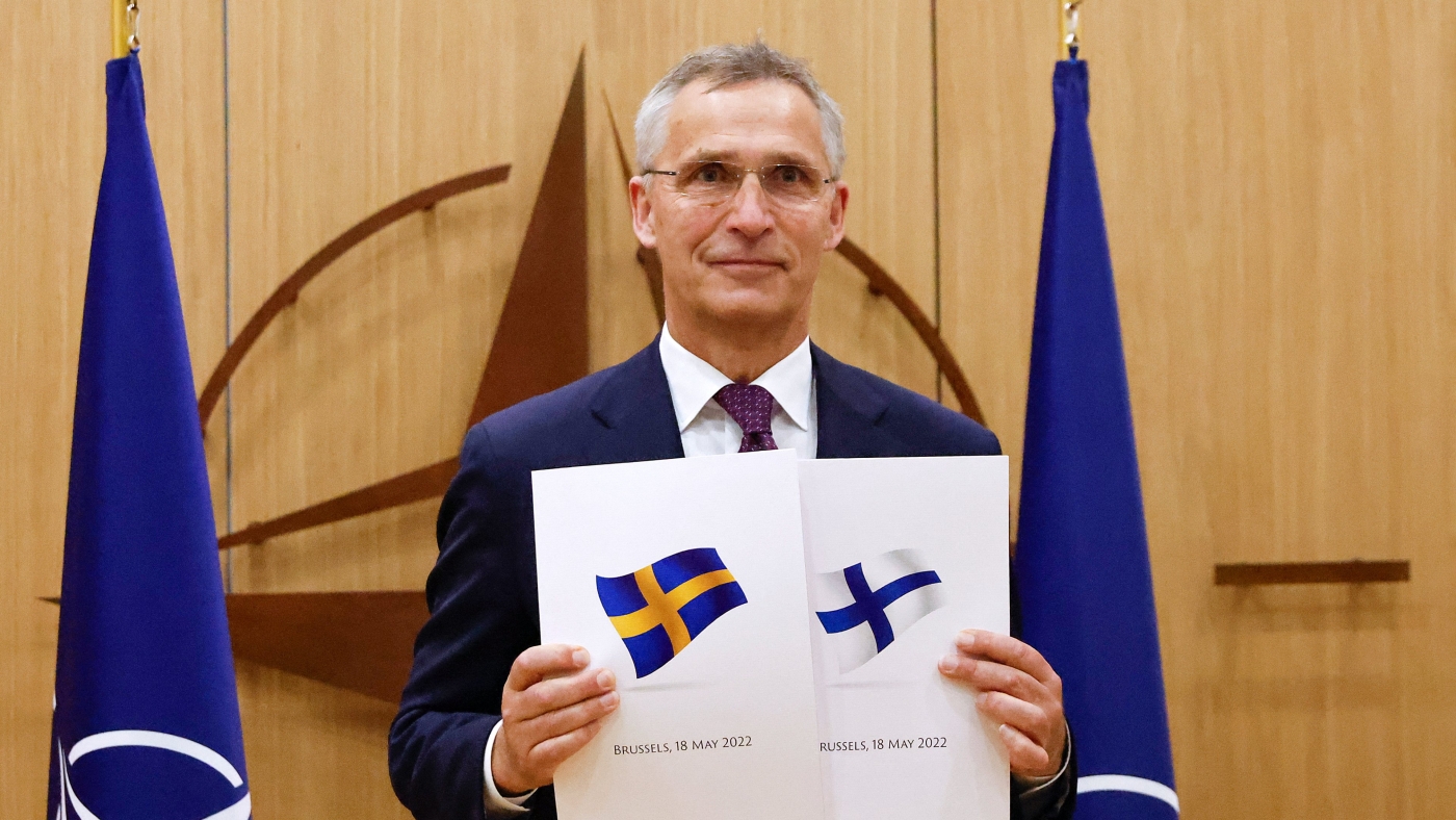 Nato Secretary-General Jens Stoltenberg poses with application documents presented by Sweden and Finland's envoys in Brussels, on 18 May 2022 (AFP)