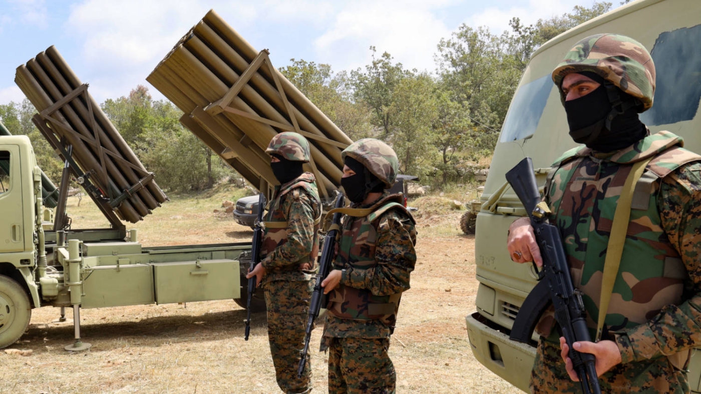 Lebanese Hezbollah fighters stand near multiple rocket launchers during a press tour in Aaramta, south Lebanon, in  May 2023 (AFP)