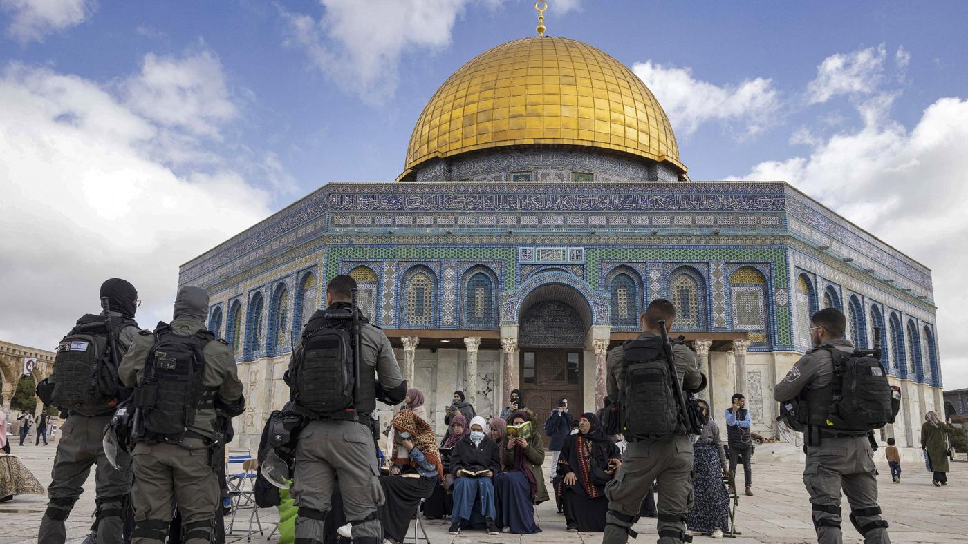 Israeli forces stand in front of Muslim women praying in front of the Dome of the Rock mosque in the old city of Jerusalem on 20 April, 2022 (AFP)