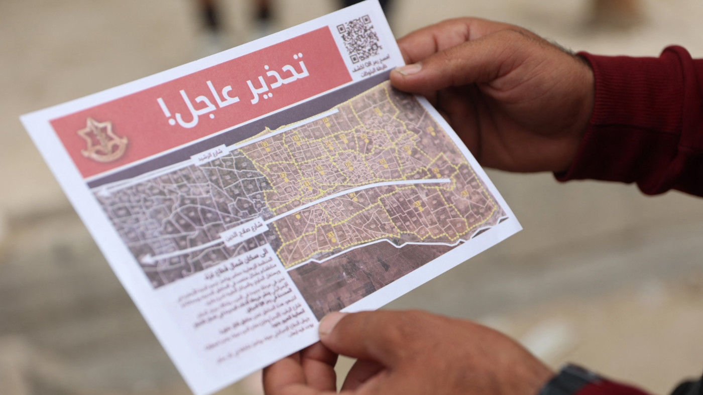 A Palestinian inspects an Israeli army  flyer, ordering people to leave  Jabalia, northern Gaza, on 6 October 2024 