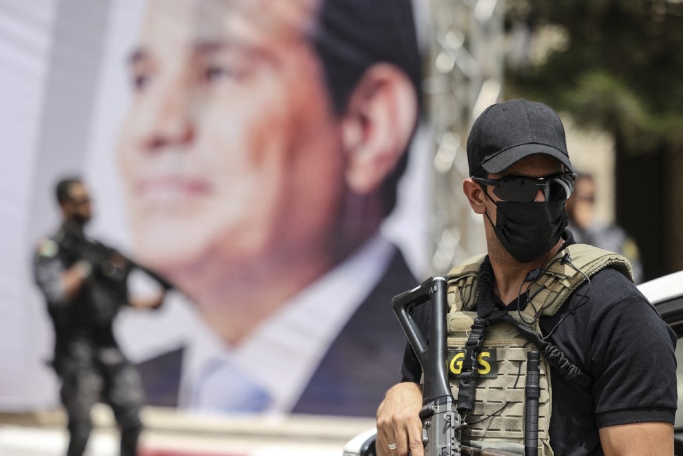 Des membres des forces égyptiennes montent la garde près d’une bannière représentant le président Abdel Fattah al-Sissi lors d’une rencontre entre le chef des services de renseignement égyptiens et des responsables du Hamas à Gaza, le 31 mai 2021 (AFP)