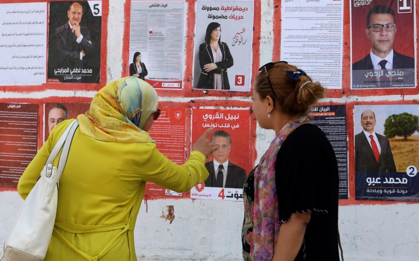 Des Tunisiennes regardent les affiches des candidats à l’élection présidentielle de 2019 (AFP)