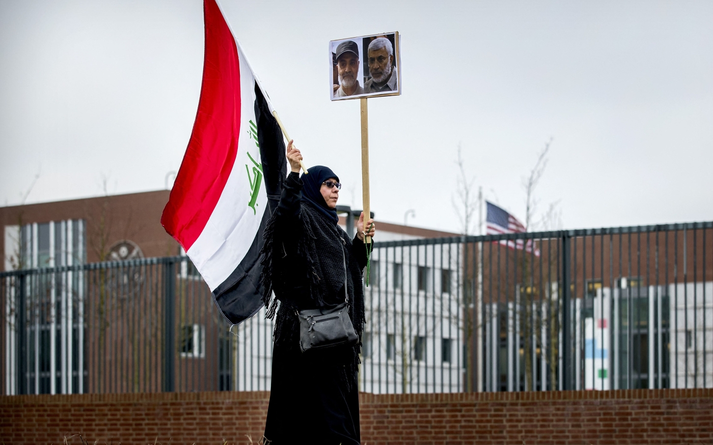 Un manifestant tient un drapeau irakien et des portraits du général iranien Qasem Soleimani (à gauche) et de son allié irakien Abou Mahdi al-Mouhandis, tous deux tués par une frappe aérienne américaine le 7 janvier 2020 (AFP)