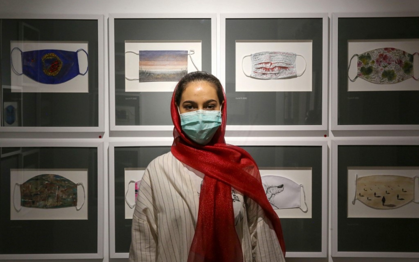 L’Iranienne Melika pose à côté d’œuvres d’art sur le thème des masques dans la galerie Cama à Téhéran, le 1er août 2020 (AFP)