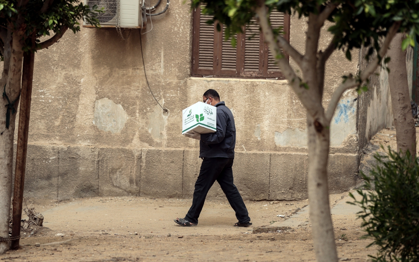 Un Égyptien transporte une boîte contenant des denrées alimentaires distribués par l'ONG Egyptian Food Bank, au Caire, le 5 avril 2020 (AFP)