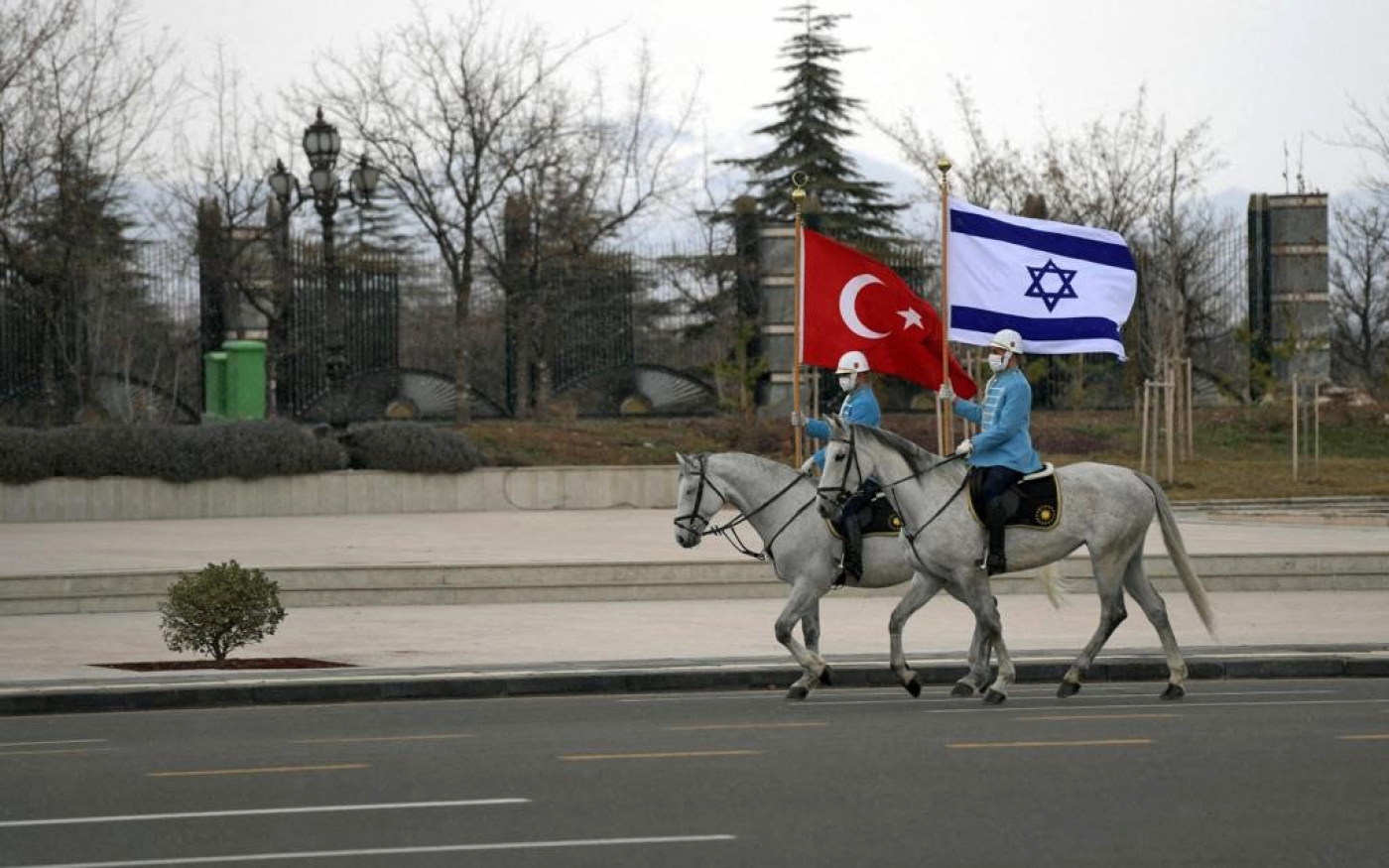 Des gardes de cavalerie turcs agitent des drapeaux israélien et turc, pour accueillir le président israélien dans la capitale Ankara (AFP)