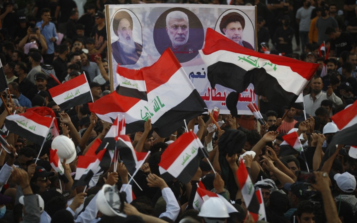 Les partisans du Cadre de coordination brandissent une pancarte représentant, de gauche à droite, le grand ayatollah Ali al-Sistani, l’ancien commandant irakien al-Muhandis, et le défunt clerc chiite irakien Mohammed Baqer al-Sadr, lors d’un rassemblement à l’extérieur de la la Zone verte à Bagdad, le 12 août 2022 (Ahmad Al-rubaye / AFP)